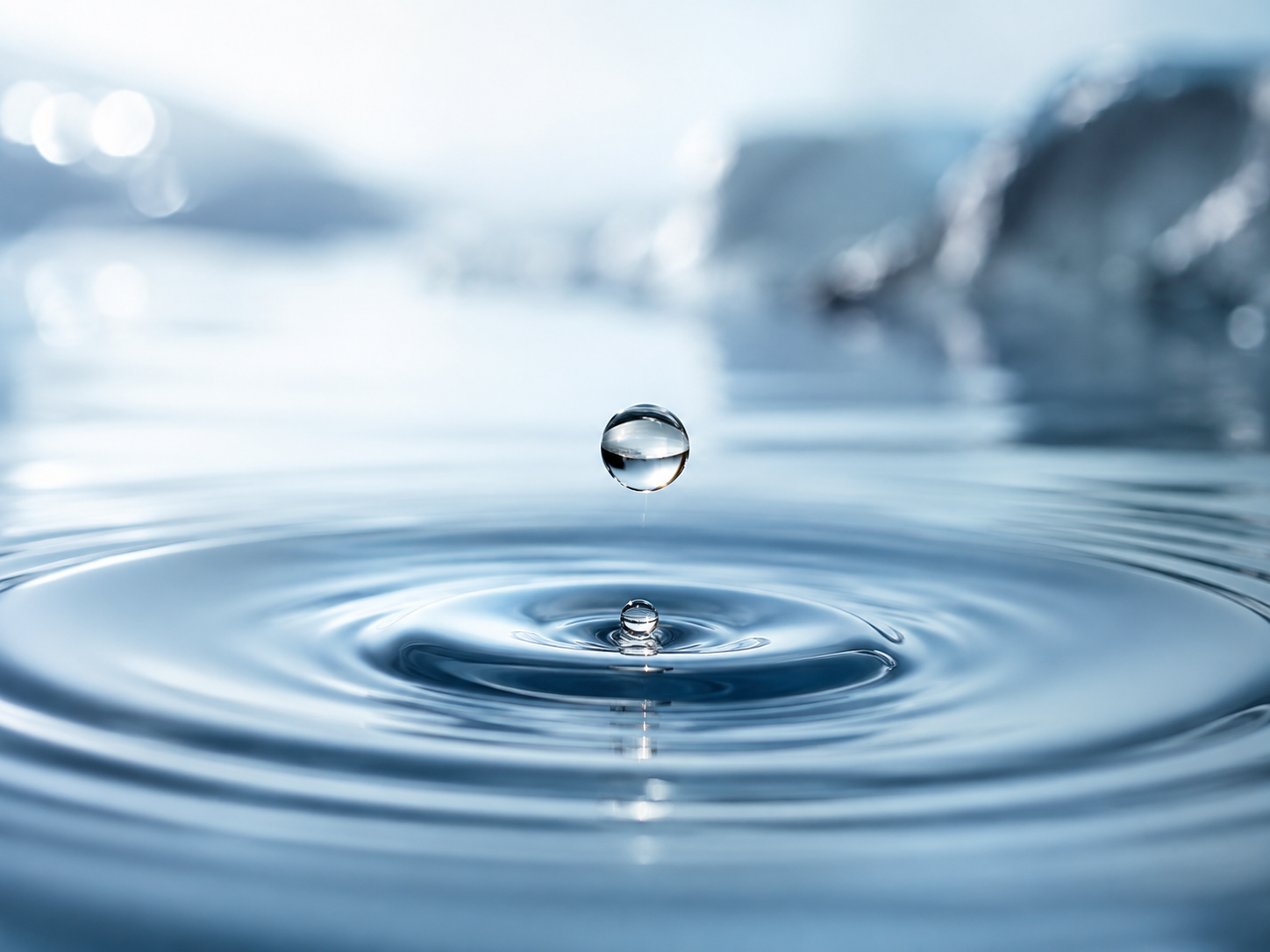 A single water droplet creating gentle ripples across a still spring-fed pool